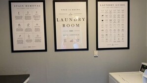 Un lavadero con zona de autoservicio, guía para quitar manchas y manual de lavado en la pared.
