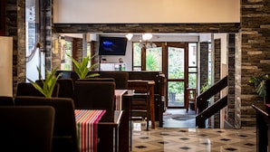 A restaurant with a stone wall, a TV mounted on the wall, and a staircase leading to an outdoor area. - Machu Picchu Adventure House (Machu Picchu)