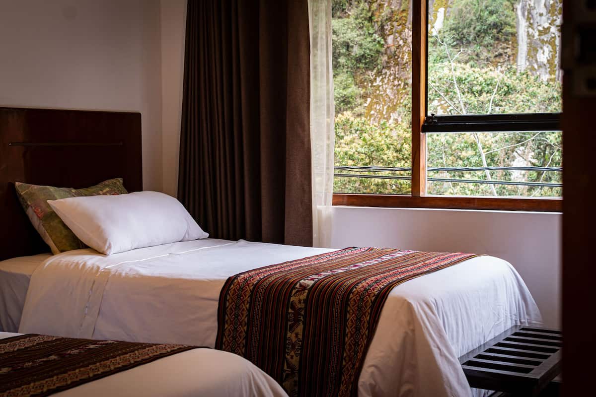 Ein Schlafzimmer mit Bett, einem Fenster und Blick ins Grüne sowie einer Kopfteil.