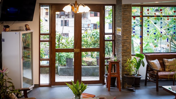 A room with a large window, a television, a refrigerator, and a seating area with a sofa and a chair. - Machu Picchu Adventure House (Machu Picchu)