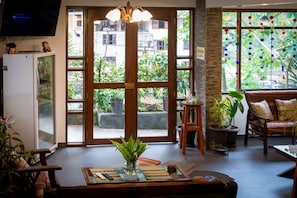 A room with a large window, a television, a refrigerator, and a seating area with a sofa and a chair. - Machu Picchu Adventure House (Machu Picchu)