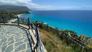 Eine Steintreppe führt zu einem Aussichtspunkt an der Küste, mit Holzzaun und Kakteen.