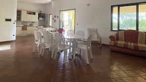 Ein geräumiger Wohnbereich mit Esstisch und Stühlen, einer Couch und einer Küche im Hintergrund.