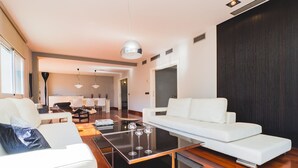 A modern living room with a white sofa, a glass coffee table, and a dining area in the background. - Cubo's Gibralfaro House Center / private pool / air conditioning (Málaga)