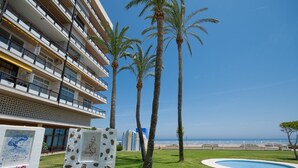 Un hôtel doté de nombreux balcons, de palmiers, d’une piscine et offrant une vue sur l’océan.