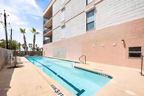 Enjoy a refreshing swim in the pool surrounded by a garden with palm trees and a concrete deck.