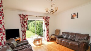 A living room with a brown leather sofa, a television, and a wooden floor. - Tilladavin House (Kilmore)