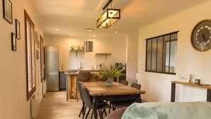 A modern kitchen with a dining area, wooden flooring, and a large clock on the wall. - Maison Avec Jacuzzi, Calme ET Detente EN Nature (Chepy)
