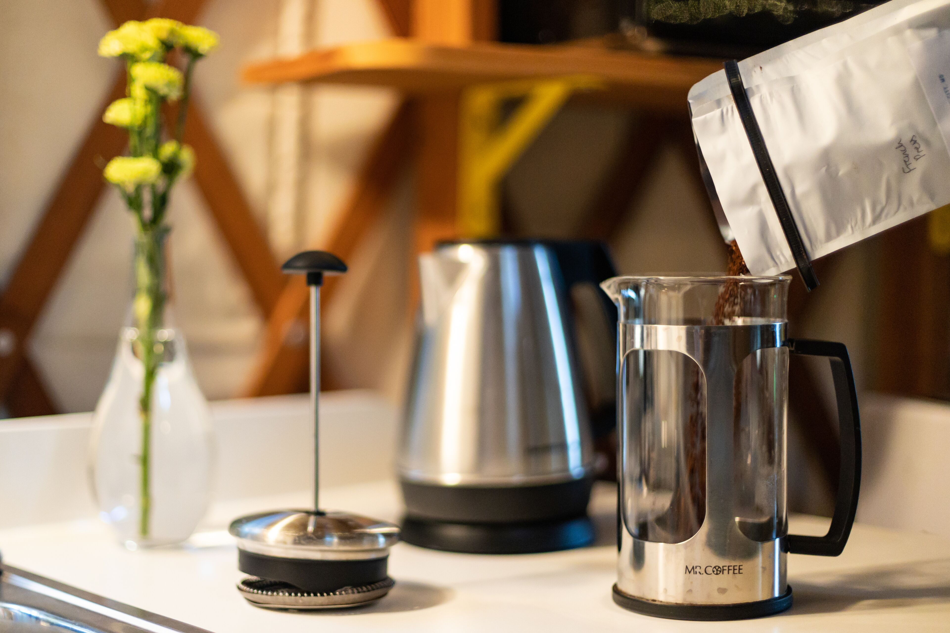 A coffee maker with a clear glass carafe, a kettle, and a small container on a countertop.