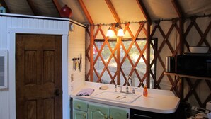A compact kitchen with a sink, two cabinets, and a microwave. - Yurt Floating in the Forest (Holts Summit)
