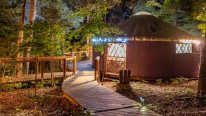 A yurt with a wooden deck leading to it, surrounded by trees. - Yurt Floating in the Forest (Holts Summit)