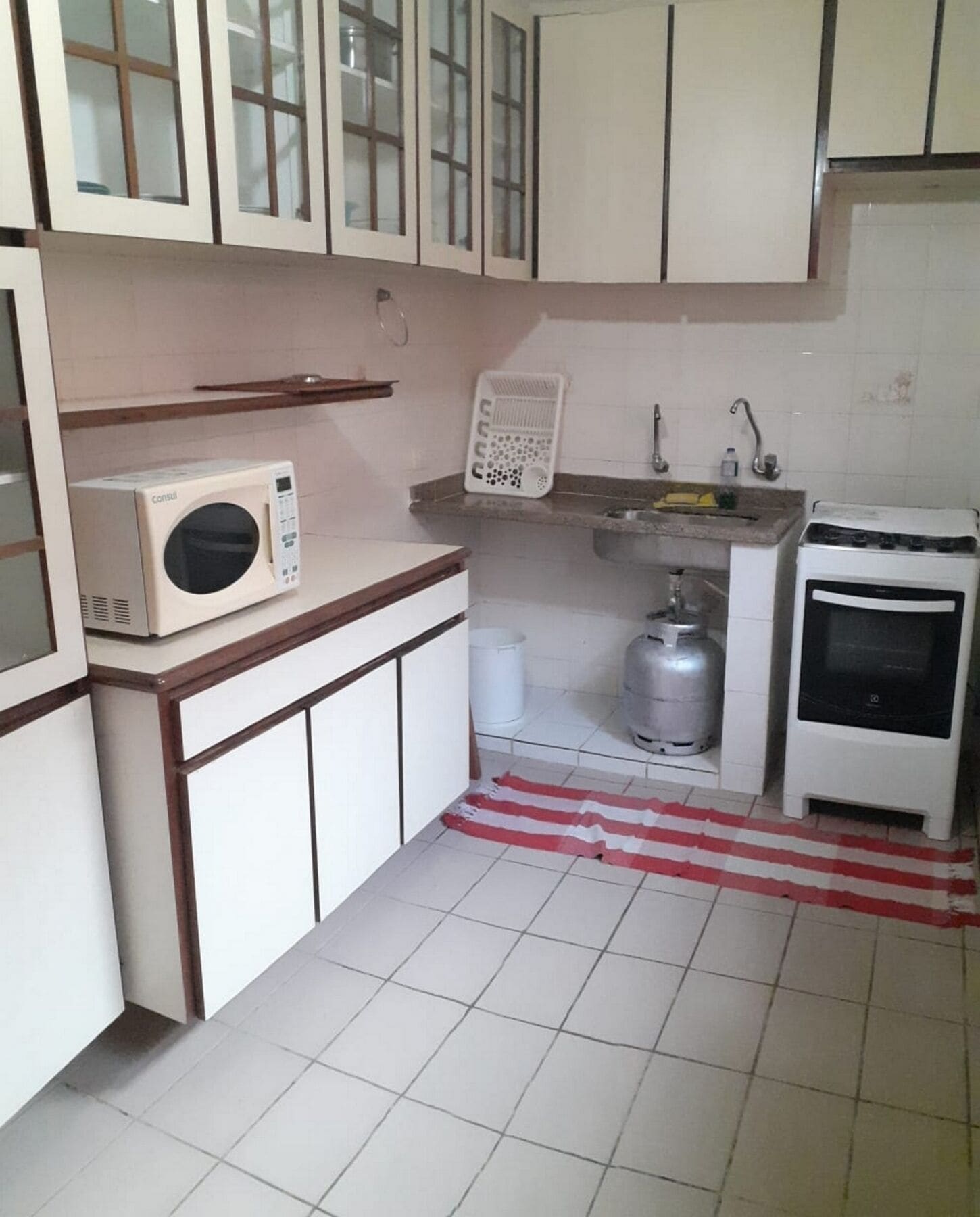 A small kitchen with white cabinets, a microwave, a gas stove, and a sink.