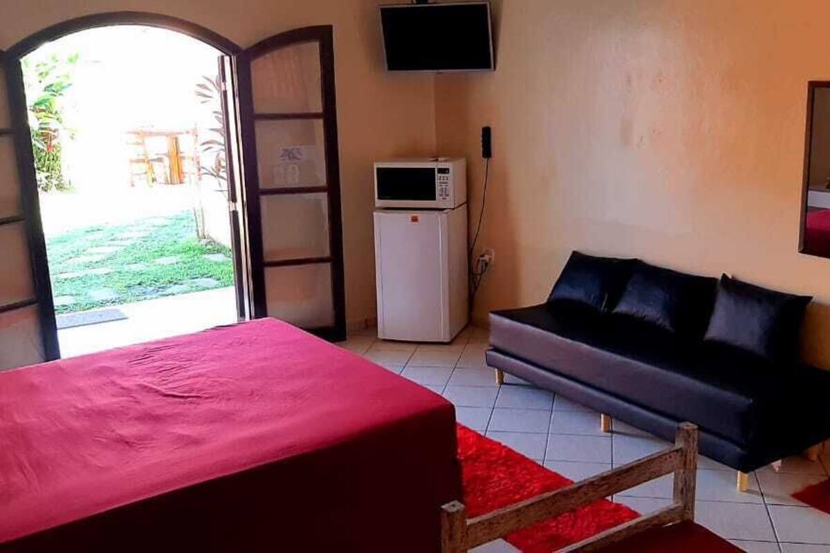 Une chambre avec un lit, un canapé, une télévision et un petit réfrigérateur.