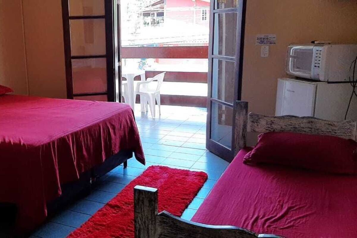 Une chambre avec deux lits, une échelle en bois, une moquette rouge et une vue sur l’extérieur.