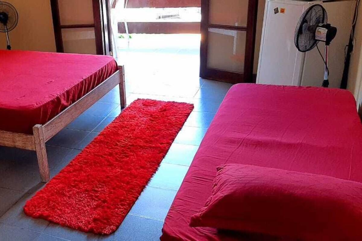 Une chambre avec deux lits, chacun doté d’un matelas et d  ’oreillers rouges, et un tapis rouge sur le sol.