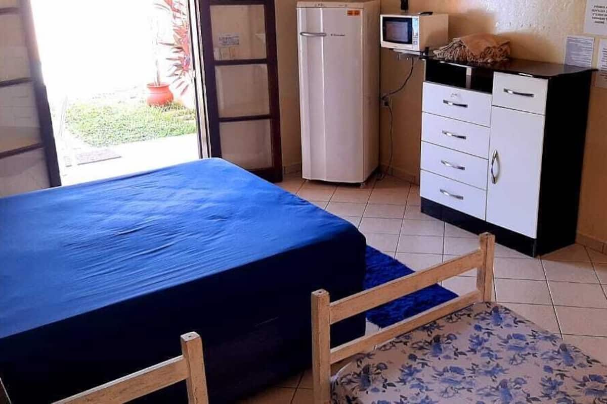 Une chambre équipée d’un lit, d’un bureau, d’un réfrigérateur et d’une télévision.