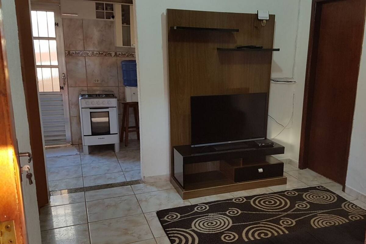Un espace de vie compact comprenant un coin cuisine, un téléviseur à écran plat et un tapis à motifs.