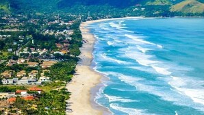 A coastal town with a beach, houses, and a lighthouse. - Pousada Villa Garden (São Sebastião)
