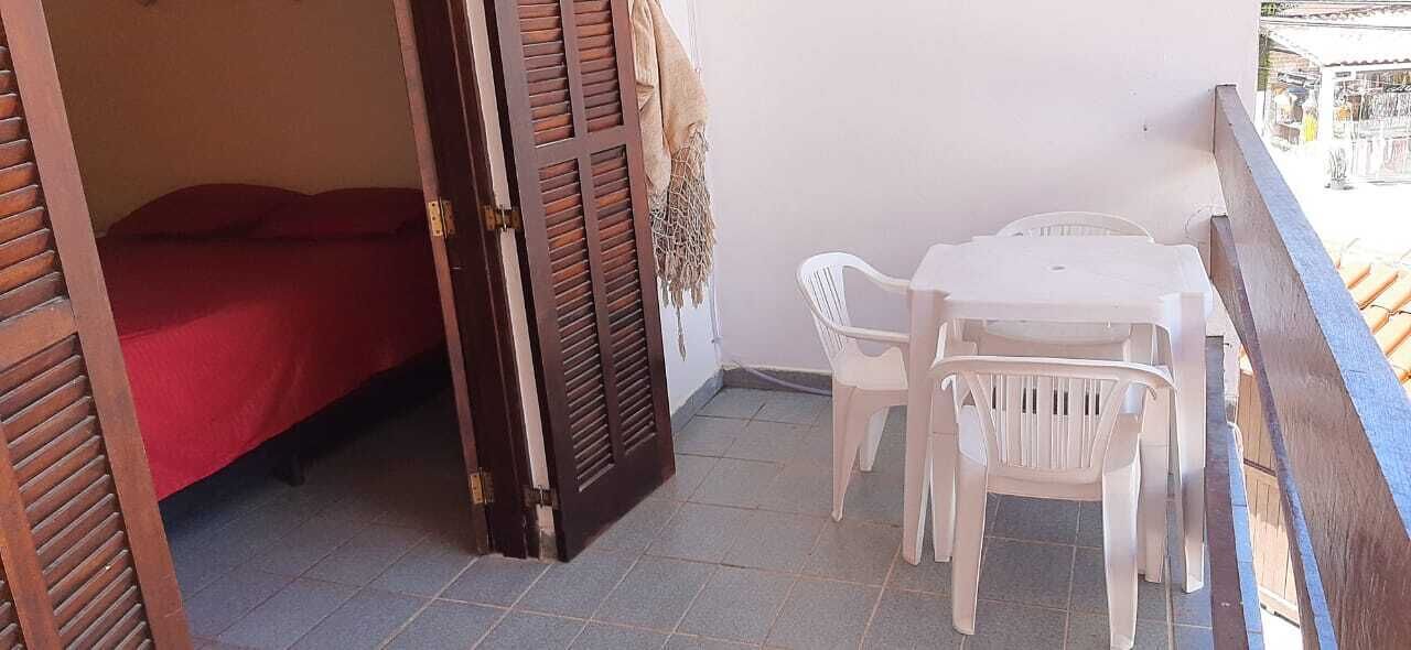 Une chambre avec un lit, une table et des chaises, et un balcon doté d’une balustrade.