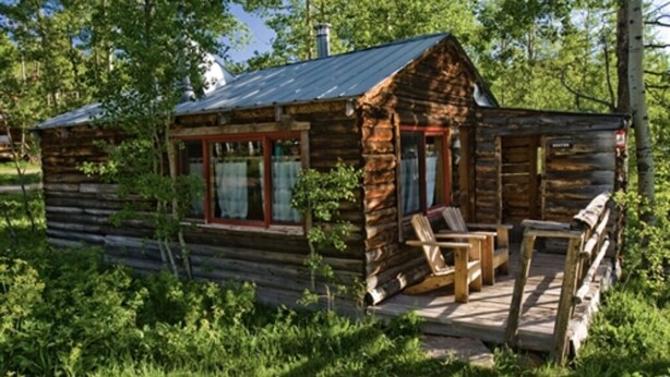A rustic log cabin with a porch and outdoor seating area. - Beaver Cabin - Cozy rustic cabin (Clark)