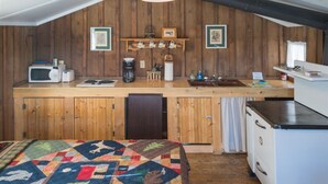 A compact kitchen with wooden cabinets, a microwave, a coffee maker, and a sink. - Bakers Cabin - A Cozy Rustic One-Room Cabin (Clark)