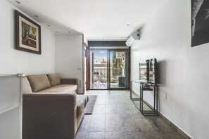 A modern living room with a sofa, a TV stand, and a sliding glass door leading to an outdoor area. - Home2Book Cozy Apartment Playa del Inglés (Playa del Ingles)