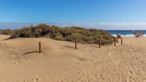 Una playa arenosa con un puesto de salvavidas y una barrera de cuerda.
