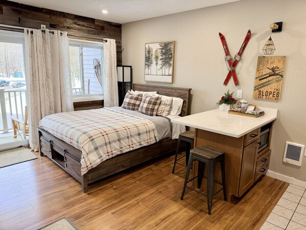 Een slaapkamer met een houten bed, een bureau en een stoel. Er is een raam met gordijnen, een schilderij aan de muur en een decoratie met ski-thema.