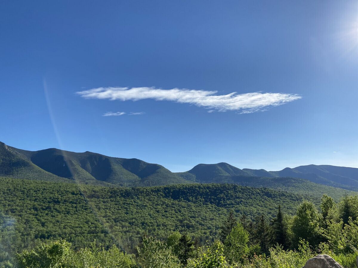 Paisagem montanhosa com floresta densa e céu limpo.