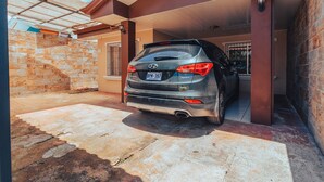 A grey Hyundai Santa Fe parked in a covered garage with a stone wall and a metal gate. - NOMADS IDEAL PROPERTY 5 MINUTES FROM LA FORTUNA (la fortuna)