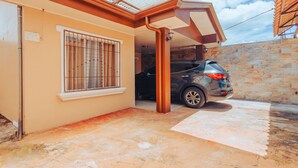 A car parked in a covered driveway of a building with a stone wall and a metal roof. - NOMADS IDEAL PROPERTY 5 MINUTES FROM LA FORTUNA (la fortuna)