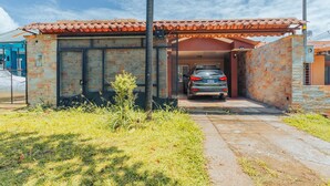 A car parked in a covered garage with a tiled roof, stone walls, and a metal gate. - NOMADS IDEAL PROPERTY 5 MINUTES FROM LA FORTUNA (la fortuna)