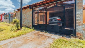 A car parked inside a metal garage attached to a brick building with a tiled roof. - NOMADS IDEAL PROPERTY 5 MINUTES FROM LA FORTUNA (la fortuna)