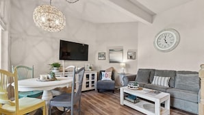 Una sala de estar con televisor, sofá, mesa de centro y comedor.