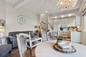 A modern kitchen with white cabinets, a microwave, and a dining area with a white table and chairs. - Waterfront, Whitefish Lake apartment! (Whitefish)