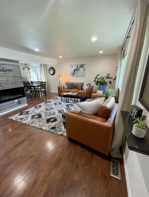 Relax in this stylish living room with a comfortable sofa, dining area, and large window.
