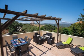 En terrasse med pergola, spisebord, stole og loungesæde.