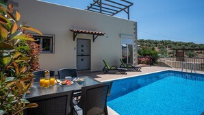 Een modern buitenzwembadgedeelte met een eettafel, stoelen en een pergola.