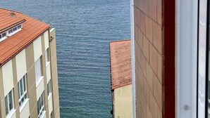 Vista al mar desde un balcón, con edificios en primer plano.
