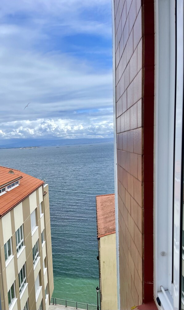 A view of the sea from a balcony, with buildings in the foreground. - Playa y Ciudad (Ribeira)