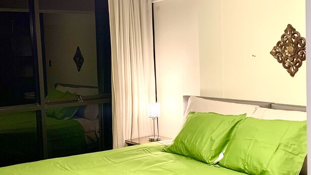 Ett hotellrum med en säng, ett nattduksbord, en lampa och en spegel.
