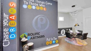 A modern hotel lobby with a large promotional poster, a reception desk, and a seating area with a colorful rug. - Stylish Townhouse in Central Houston (Houston)