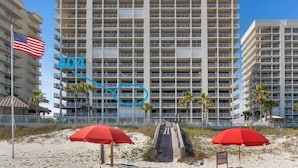 A multi-story hotel with a central atrium, a beachside location, and red umbrellas on the sand.