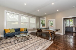Relax in this spacious living room with a sofa, coffee table, and ping pong table.