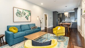 Un salon moderne avec un canapé bleu, un fauteuil jaune et une table basse en bois.