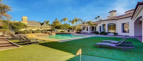 A well-maintained backyard with a swimming pool, artificial turf, and lounge chairs.