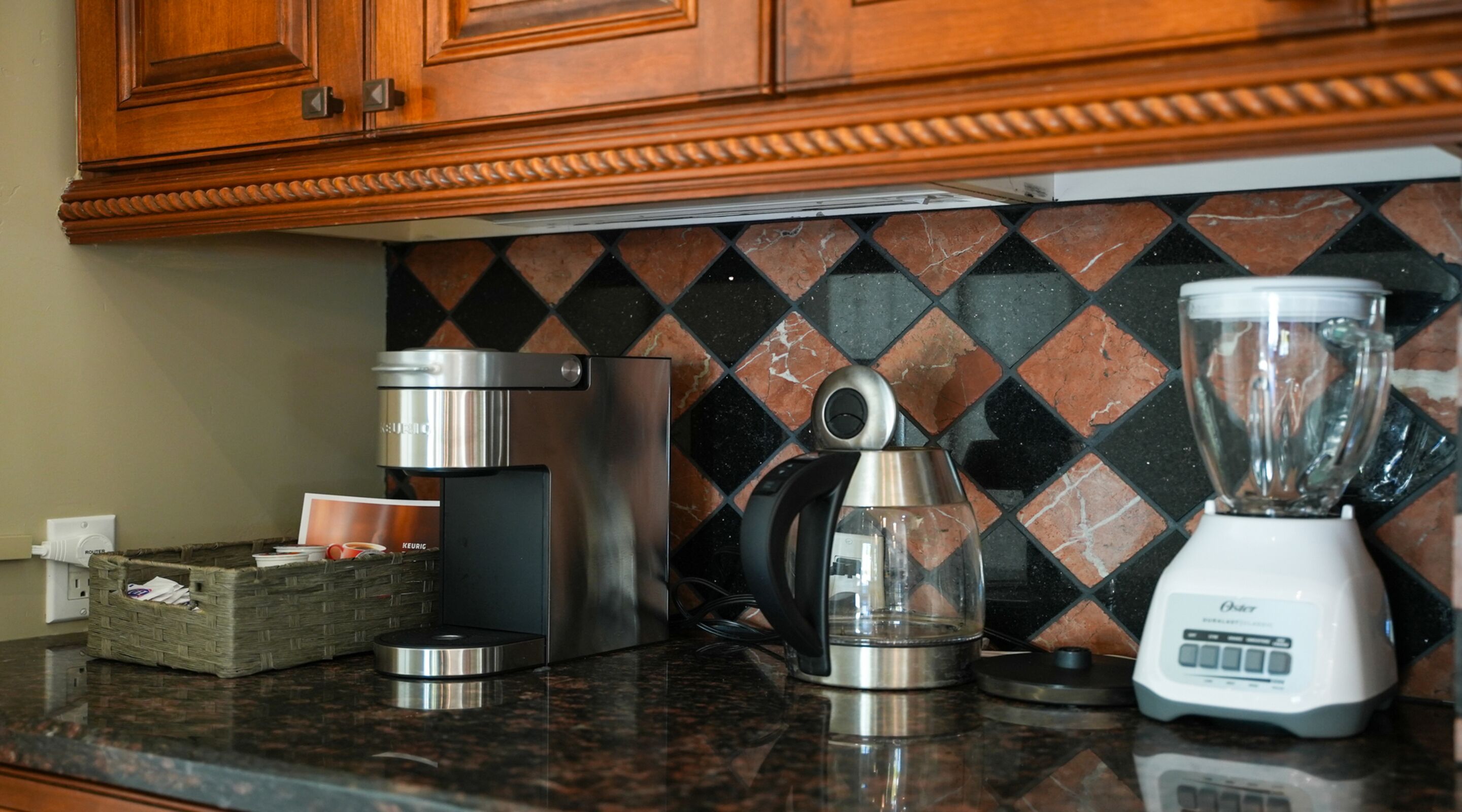 Cozinha com máquina de café, liquidificador e chaleira sobre bancada de granito.