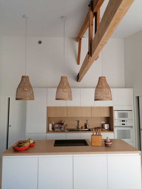 A modern kitchen with white cabinets, a wooden island, and three woven pendant lights. - Beautiful, fully renovated villa, bike path 50 meters away, beach 2 minutes away, 4 bedrooms. (Andernos-les-Bains)