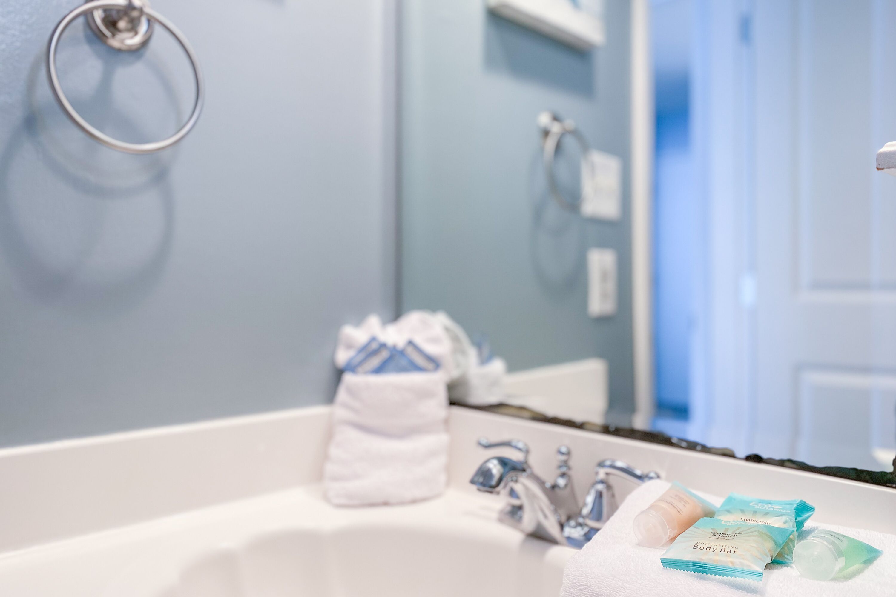 Une salle de bain avec un lavabo blanc, un porte-serviettes et des articles de toilette posés sur le comptoir.