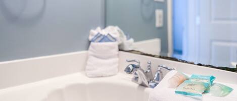 Une salle de bain avec un lavabo blanc, un porte-serviettes et des articles de toilette posés sur le comptoir.
